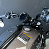 Close-up of a motorcycle handlebar with control buttons and mirror on a dark background