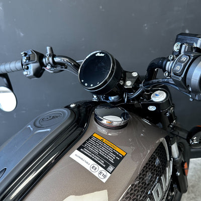 Close-up of a motorcycle handlebar with control buttons and mirror on a dark background