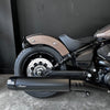 Close-up of a motorcycle's exhaust and wheel on a dark background