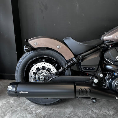 Close-up of a motorcycle's exhaust and wheel on a dark background