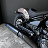 Close-up of a motorcycle with a black exhaust and visible branding on a gray floor.