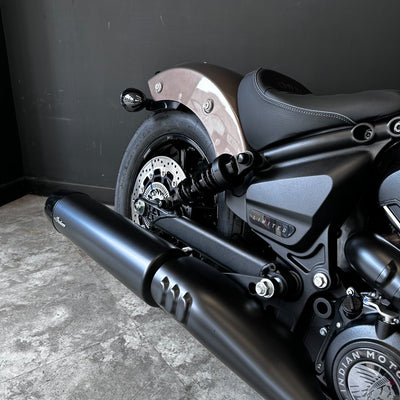 Close-up of a motorcycle with a black exhaust and visible branding on a gray floor.