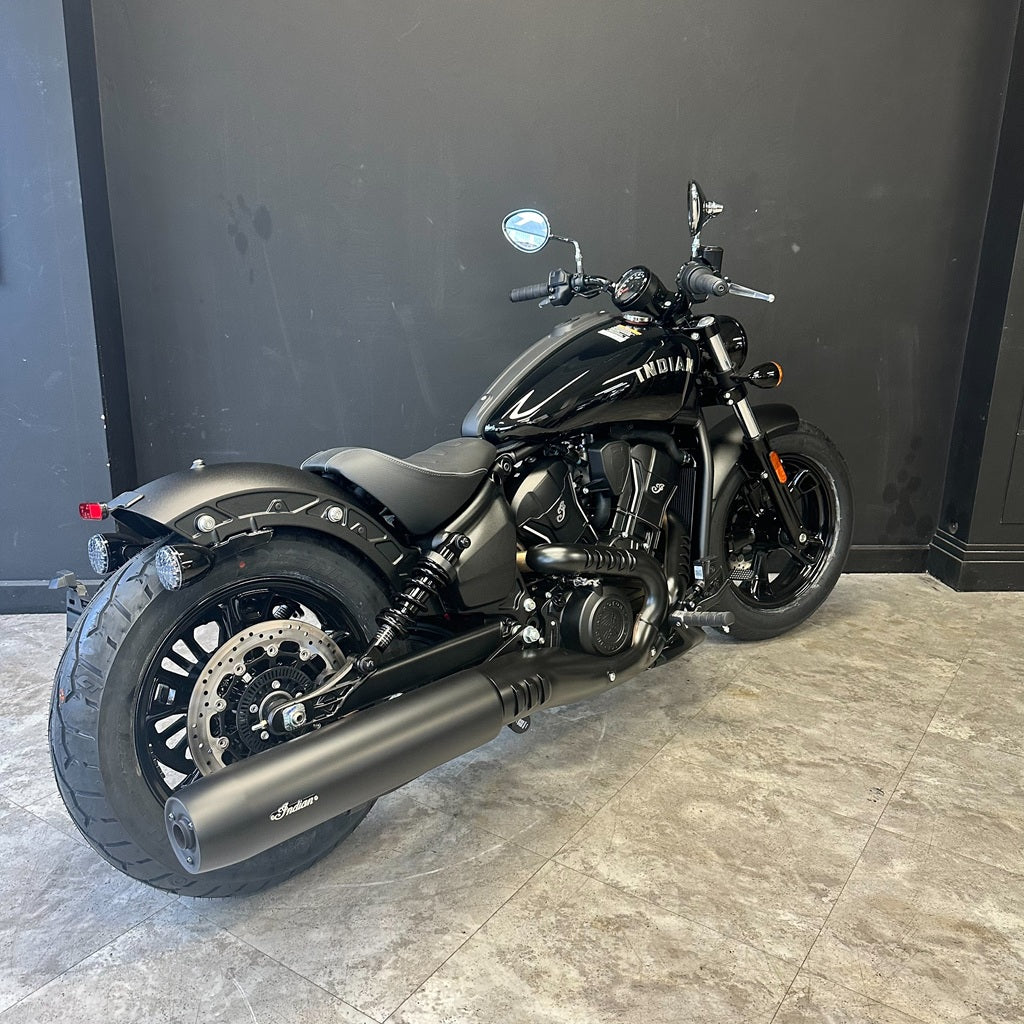 Black motorcycle on a tiled floor with a dark wall background