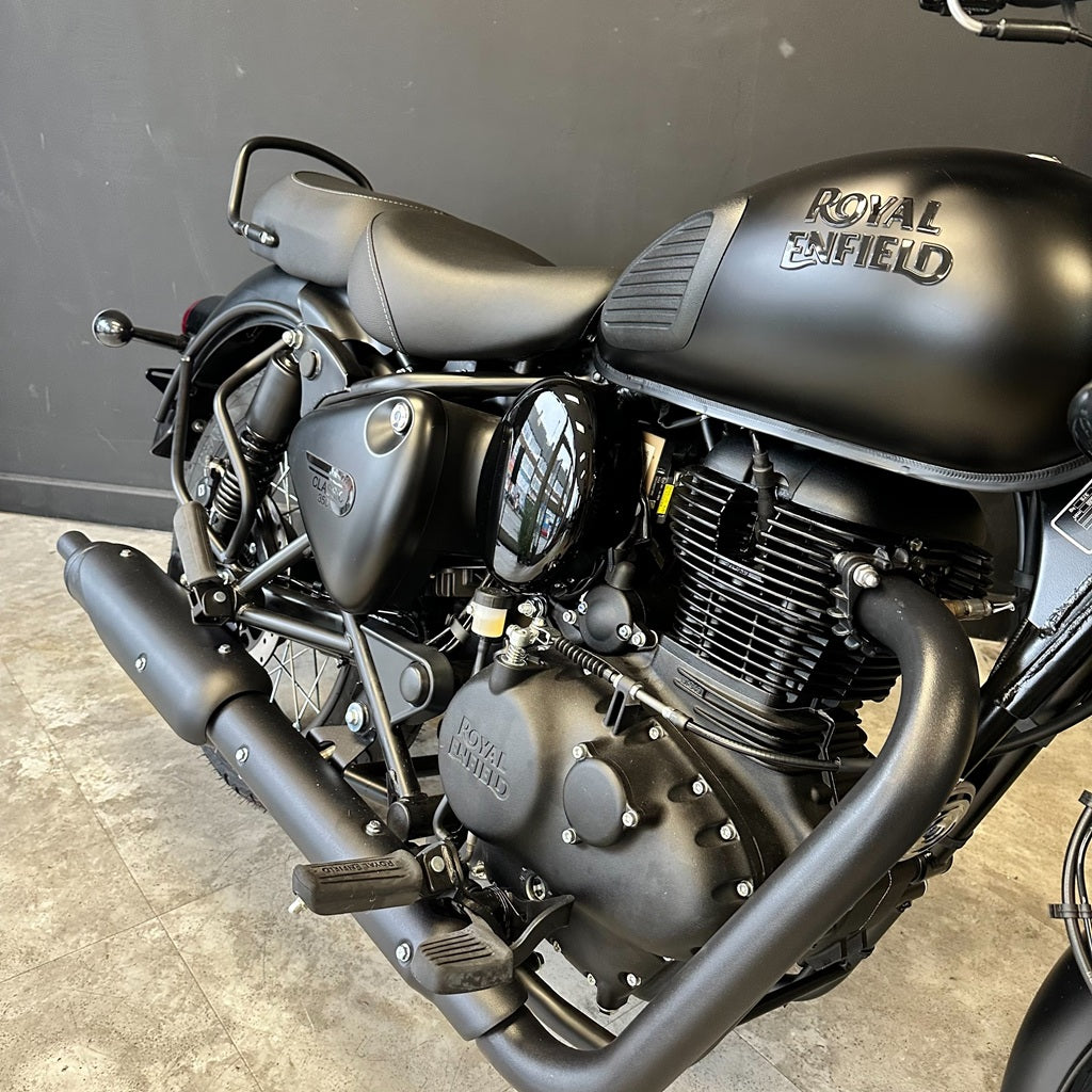 Black Royal Enfield motorcycle on a concrete floor with a gray wall background