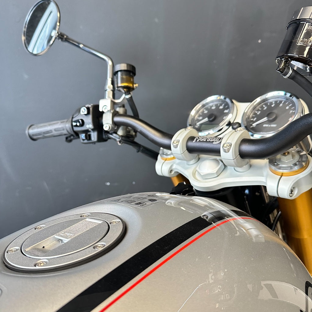 Close-up of a motorcycle's handlebar, mirrors, and dashboard against a dark background.