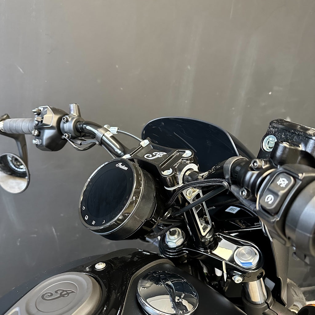 Close-up of motorcycle handlebar with control buttons and mirrors against a gray background