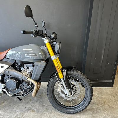Motorcycle with a black and yellow design parked against a dark wall.