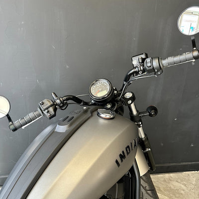 Close-up of a motorcycle handlebar with 'Indian' branding against a dark background