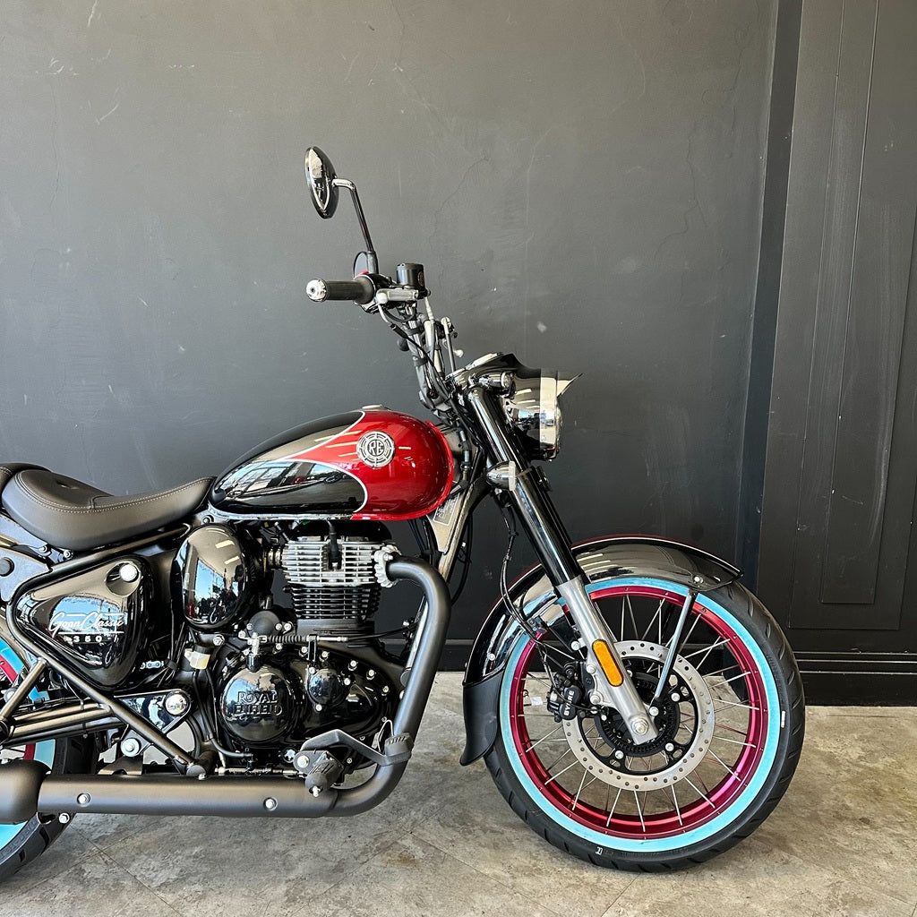Motorcycle with red fuel tank and black frame against a gray wall