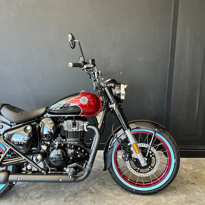 Motorcycle with red fuel tank and black frame against a gray wall