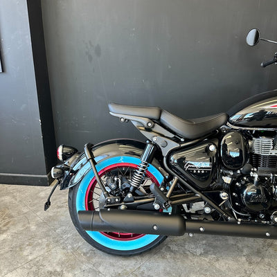 Motorcycle with black seat and blue rim against a dark wall