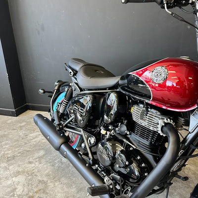 Motorcycle with a red fuel tank and black exhaust against a gray wall.