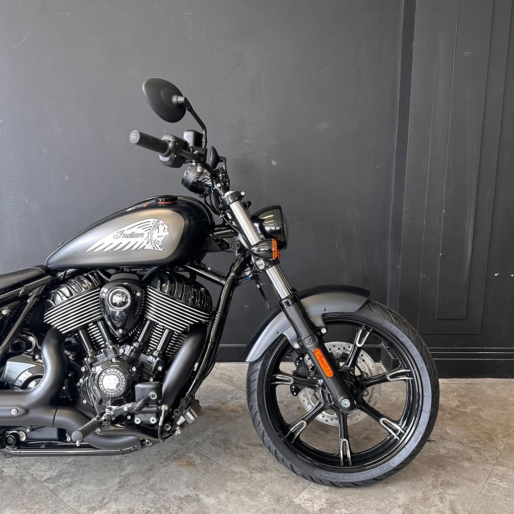 Black motorcycle parked against a dark gray wall