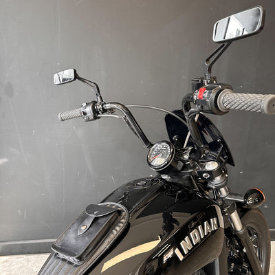 Black motorcycle with 'Indian' branding against a gray wall