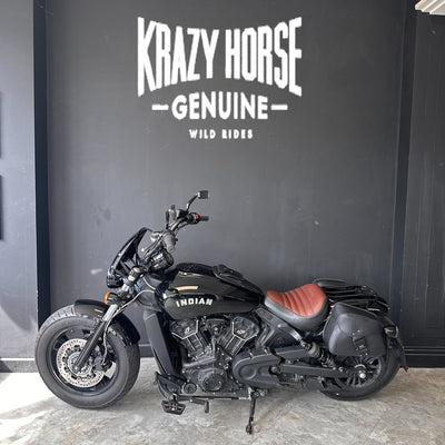 Black motorcycle with red seat in front of a black wall with 'Krazy Horse Genuine' branding.