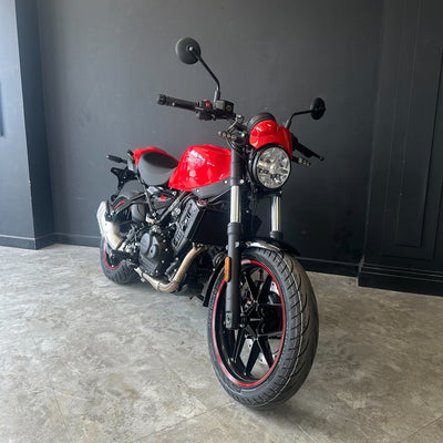 A red and black Ducati Monster 820 motorcycle parked indoors on a gray concrete floor against a dark gray wall.