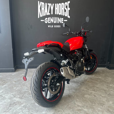 A red and black Kawasaki Zongli motorcycle photographed indoors against a dark gray wall with the text 'KRAZY HORSE GENUINE WILD RIDES' above it.