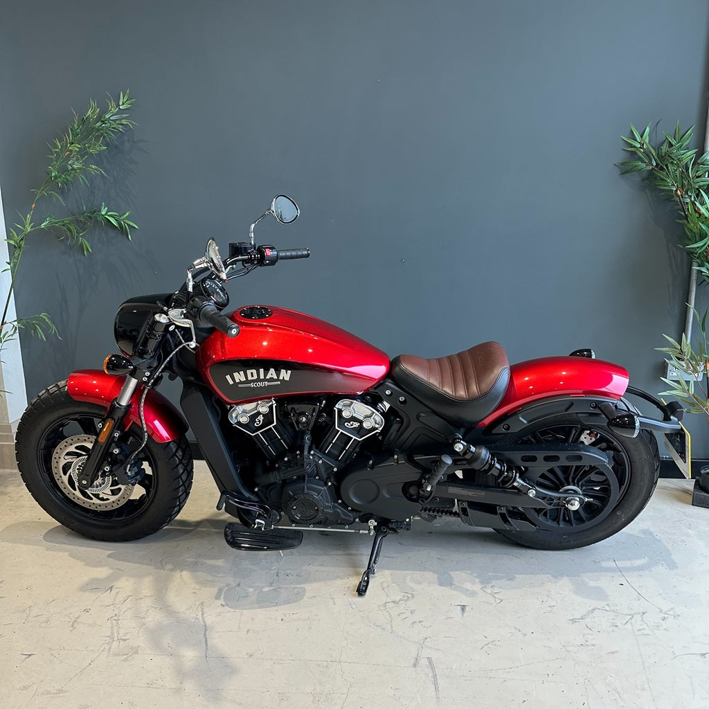 Red Indian motorcycle parked indoors with a gray wall and plants in the background