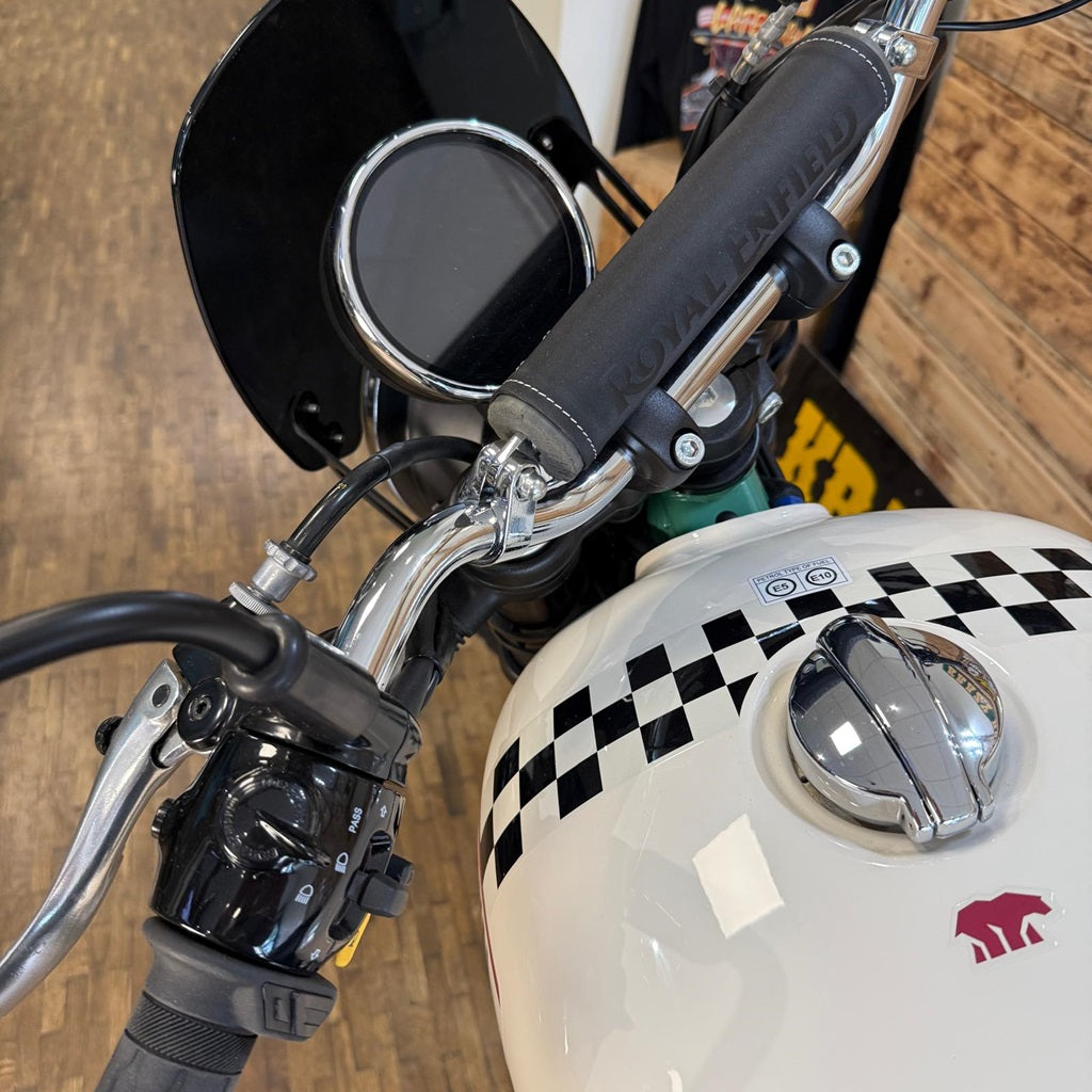 Close-up of a motorcycle handlebar with checkered helmet and visible brand logo.