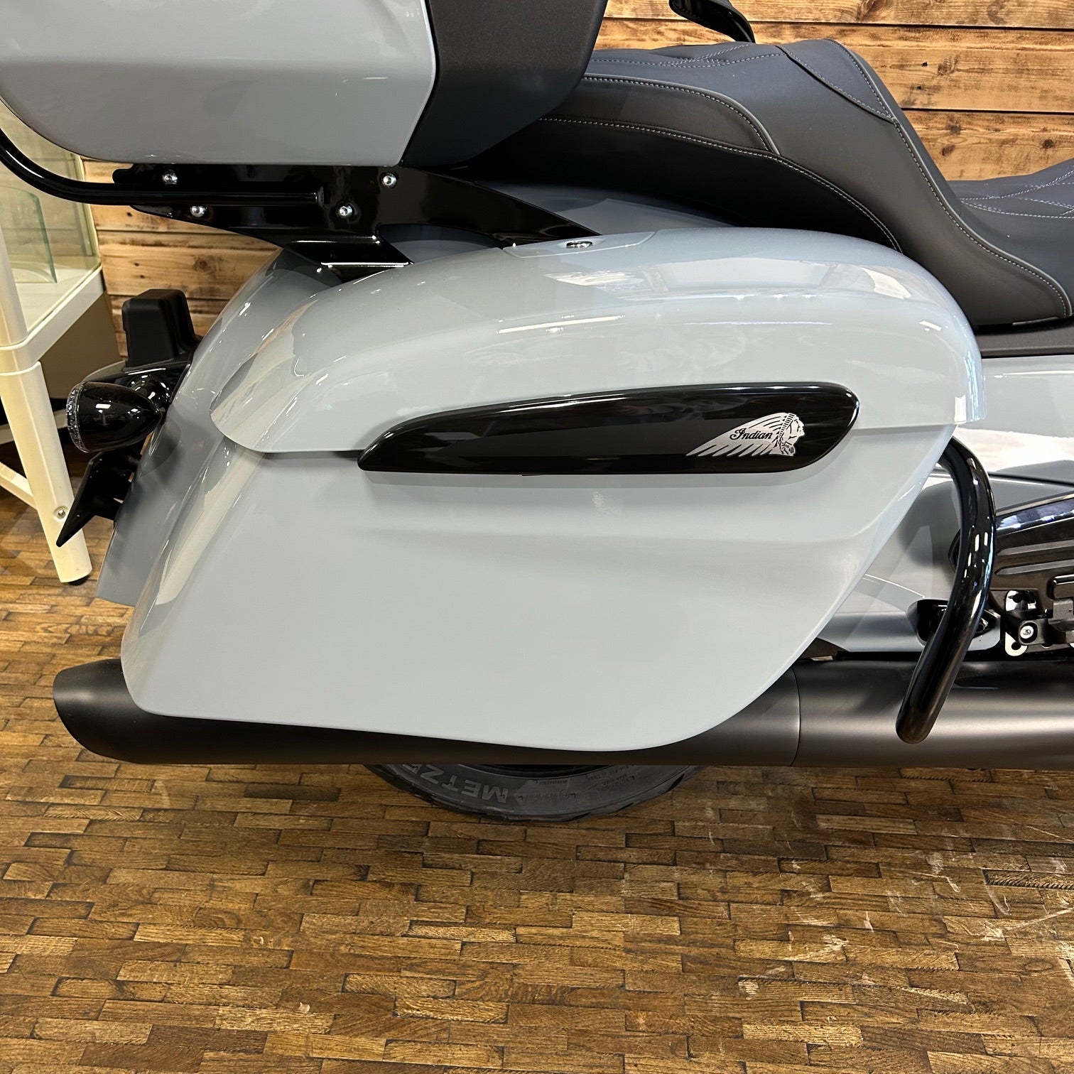 Gray motorcycle with a black exhaust on a wooden floor